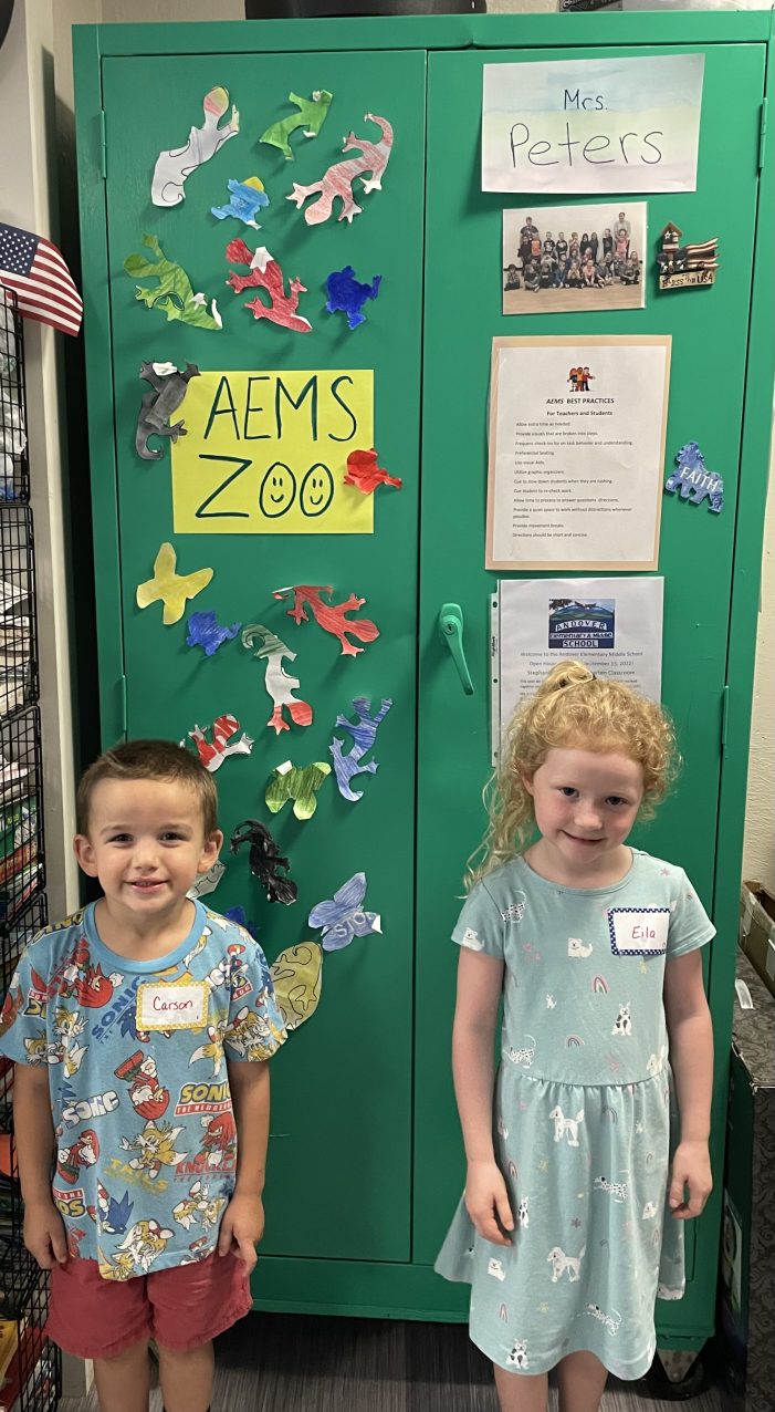 Kindergarteners Carson and Eila Stand in Front of the “Lizard Zoo”