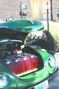 Michele Bengivengo with the all-electric 1972 VW Beetle (license plate: "72VOLTS") she and husband Chris restored and retrofitted themselves. The only liquids in the air-cooled car are brake fluid and windshield washer fluid. Though the car doesn't go far without a recharge, it's very quiet, according to Michele. Caption and photo: Larry Chase