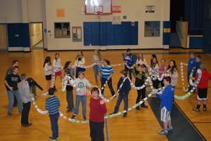 The Kearsarge Middle School students created a giant paper chain of recycled paper to symbolize "SPREADING KINDNESS: A CHAIN REACTION".The Kearsarge School District pioneered the program of distance learning when school is cancelled due to weather; the program is called "blizzard bag".  Each student is randomly assigned to a "community" to represent a cross section of the total middle school community. The school engages in an all-school read focusing on fostering kindness and respect in the school community.  Following the day away from school, staff and students met in their blizzard bag community to discuss the assignments for the day, but also focused on on building a "chain reaction of kindness" from recycled paper.  The chain was constructed from [nearly] 500 links with words of kindness printed on each.